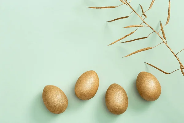 Βαμμένα πασχαλινά λαμπερά αυγά και χρυσοκίτρινο φυτό σε ανοιχτό πράσινο χαρτί. Ελάχιστη ιδέα του Πάσχα. Ανοιξιάτικες διακοπές — Φωτογραφία Αρχείου