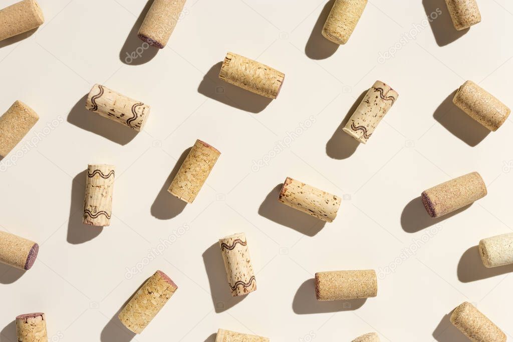 Pattern with wine corks from white and red wine on beige pastel color background with shadow at sunlight. Trend layout with bottle cap wooden cork, top view, minimal flat lay