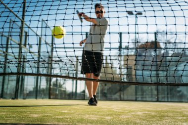 Adam raket oynuyor. Kürek topu ağa çarptı. Açık hava sporu.