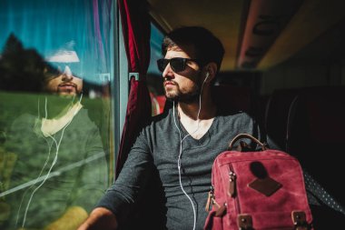 Düşünceli bir genç adam otobüse binip pencereden dışarı bakıyor..