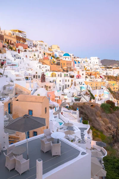 Seaside view at blue hour of traditional white wash buildings and blue dome church at the popular seaside tourist resort village of Oia on the Greek island of Santorini, Greece.