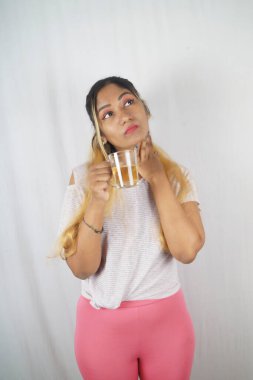 Güzel kadın beyaz arka planda dikilirken başka tarafa bakıyor.