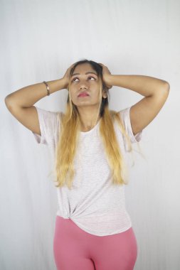 Düşünceli bir kadın beyaz arka planda dikilirken yukarı bakıyor.