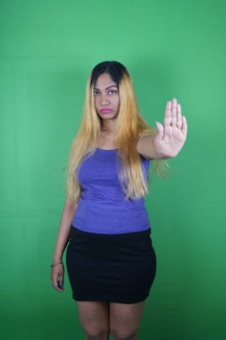 Yeşil arka planda el kol hareketi yapan sarışın bir kadın.