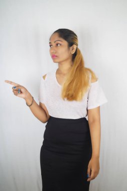 Güzel bir kadın beyaz arka planda dikilirken işaret ediyor