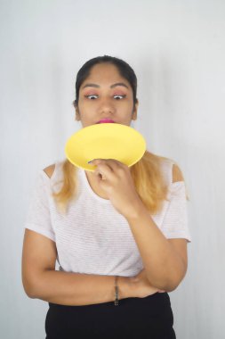 Beyaz arka planda duran boş tabağı tutan oyuncu kadın.