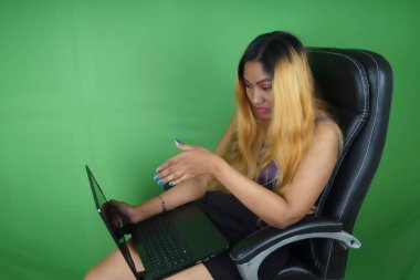 Yeşil arkaplan önünde dizüstü bilgisayar kullanan iş kadını