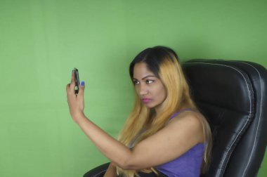 Yeşil arka planda cep telefonu kullanan güzel bir kadın.