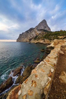 Deniz kıyısındaki büyük dağda gün doğumu ve uçurumun manzarası.