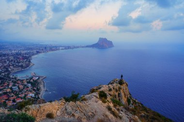 Kişi, sahile ve denize bakarak bir dağın zirvesine tırmandı. Calpe alicante.