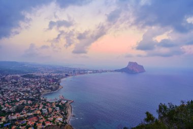 Günbatımında bulutlu bir günde denizin ortasında kayalarıyla Alicante Koyu 'nu ara..