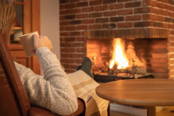 Kışın şöminenin önünde kahve içen bir kadın..