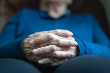 Huzurlu ve rahat bir tavırla parmaklarını çapraz yapmış yaşlı bir kadının elleri..