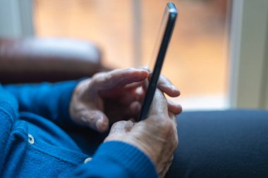 Üst düzey kadın elleri cep telefonu tutuyor ve ekrana dokunuyor..