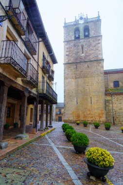 Yoğun sisli bir günde eski evlerin yanındaki eski ortaçağ taş kilisesi. Riaza Segovia.