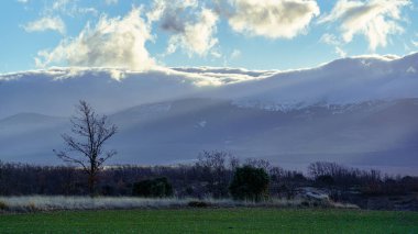 Yüksek karlı dağlardan gelen güneş ışınlarıyla büyülü kış manzarası.