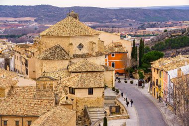 Cuenca, İspanya 'da yürüyen insanların bulunduğu ortaçağ taş binaları ve yol manzarası.