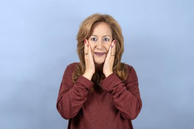 Şaşırmış bir yüz ve elleri olan duygusal bir kadın, mavi stüdyo geçmişi var..