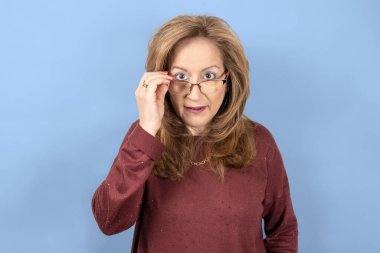 Şaşkın bakışlı, mavi stüdyo geçmişi olan bir kadın..