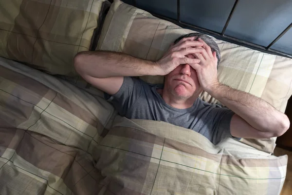 Uykusuzluk çeken ve yorgunluktan burnundan soluyan bir adam..