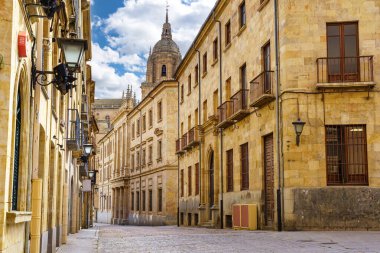 Salamanca şehrinin arka planında katedralin kubbesi olan ortaçağ sokağı..
