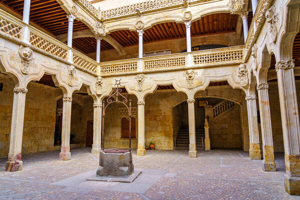 Средневековый двор с каменными арками и хорошо в центре корпуса, Саламанка.