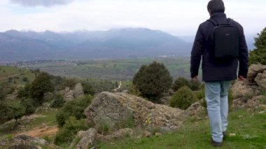 Dağlarda kayaya tırmanıp temiz hava soluyan bir adam..