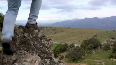 Dağdaki kayaya tırmanıp telefonla arayan bir adam..