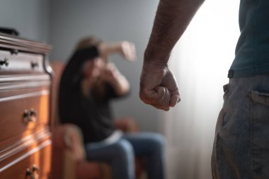 Yumruğunu sıkan ve karısını ona saldırmakla tehdit eden bir adam, evde cinsiyet şiddeti.