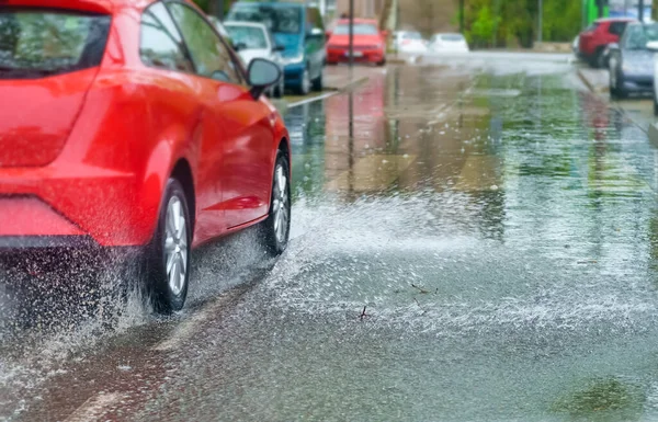 Çok yağmurlu bir gün ve su birikintisinden geçerken araba su sıçratıyor..