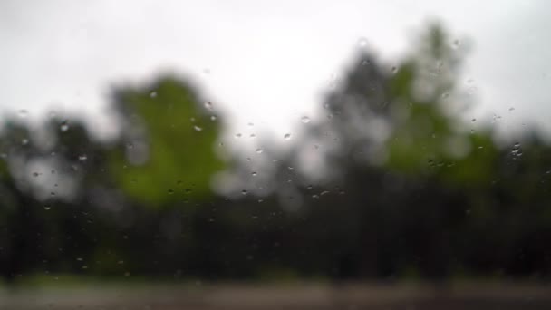Regentropfen fallen auf die Scheibe und vorbeifahrende Autos. — Stockvideo