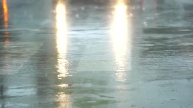 Asfalta düşen yağmurun yavaş akışı ve su birikintilerinden geçen arabalar..
