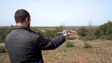 Man holding a drone with his hand and taking off the flight with the remote control.