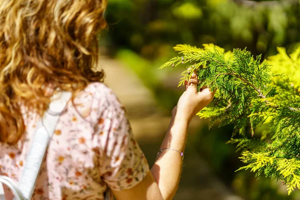 Bir kadın bir bitkiyi eliyle alıp güzelliğini gözlemliyor..
