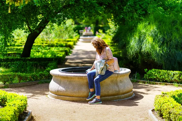 정원 중앙에 있는 민물의 작은 샘에 앉아 있는 여자. — 스톡 사진