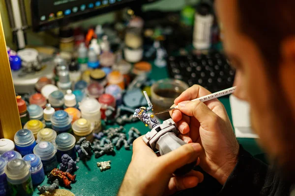 Masa oyunlarının küçük minyatürlerini farklı renklerle boyayan adam
