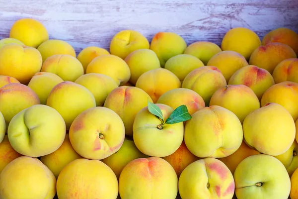 İştah açıcı görünümlü bir sürü sarı şeftali bir konteyner kutusuna konur.