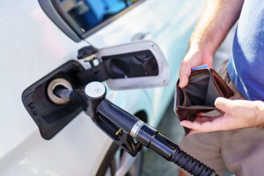 Hands of a man showing the empty wallet after refueling at a gas station