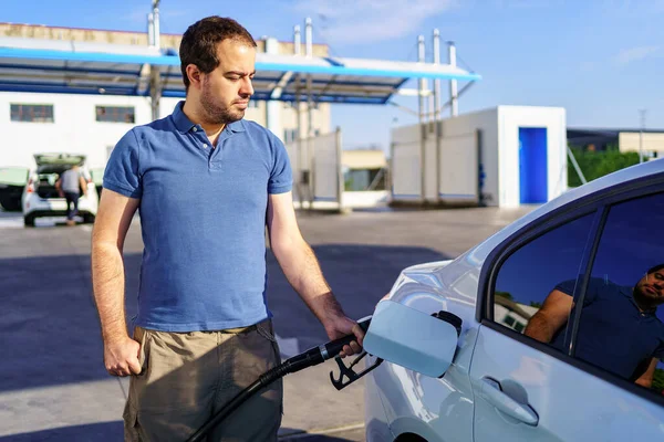 一个白种人年轻人在加油站给燃料车的油箱充电 — 图库照片