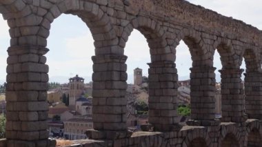 Arka planda ortaçağ binaları olan Segovia su kemerlerinin taştan kemerleri, İspanya