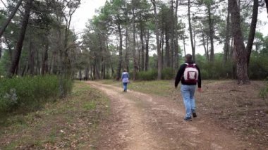 Man and woman hiking along a forest path along with their little dog