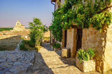 San Esteban de Gormaz, Soria 'da arka planda eski taş evleri ve Romanesk kilisesi olan güzel bir sokak.