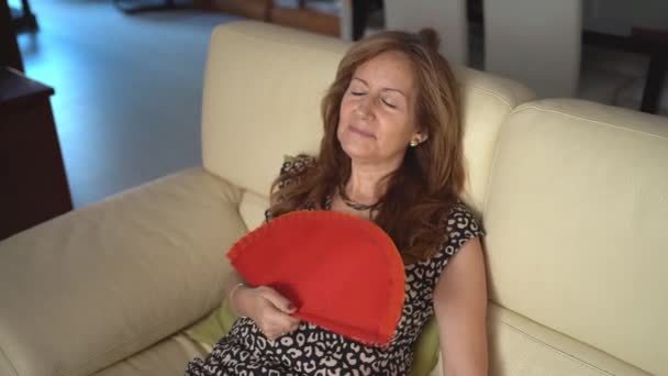 Olgun Bir Kadın Kanepede Oturur Yazın Yüksek Sıcağında Bir Yelpazeyle — Stok video