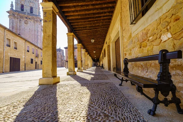 Arcades under the old stone buildings and wooden bench to sit in the Burgo de Osma, Soria