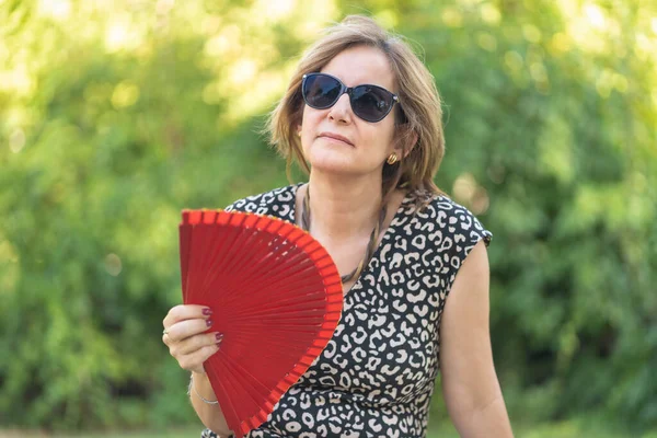 Mature woman with symptoms of menopause with strong hot flashes and fanning