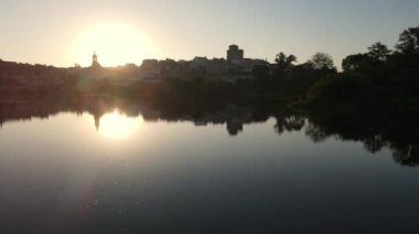 River Tormes with calm water in a dreamy sunrise with the medieval town of Alba de Tormes in the background