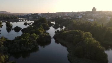 Medieval city on a hill and with the river at its feet in a golden sunset and clear sky with fog, Alba de Tormes, Salamanca