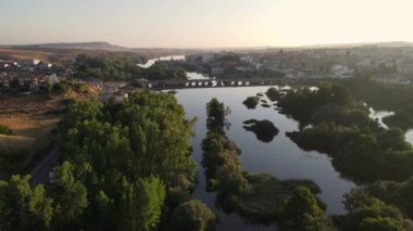 A view of drone river of calm water with medieval bridge at the foot of the old city of Alba de Tormes, Spain