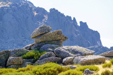 Large rocks stacked with strange shapes with large rocky mountain in the background in the Community of Madrid, Spain