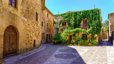 Panoramic view of stone houses with flowers and vines on the walls in the picturesque village of Pals, Girona, Spain
